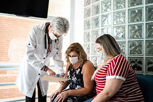 Doctor with patient and patients daughter reviewing medical information