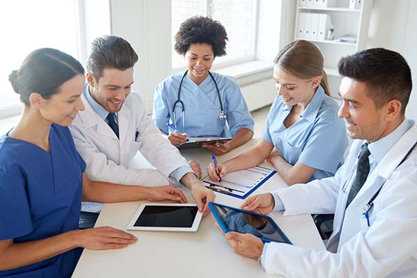 Group of medical professionals around a table reviewing medical charts
