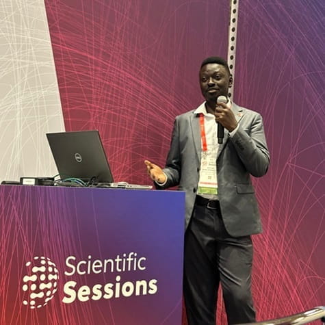 Dr Ateh Stanislas presenting from behind a podium with a Scientific Sessions banner on it