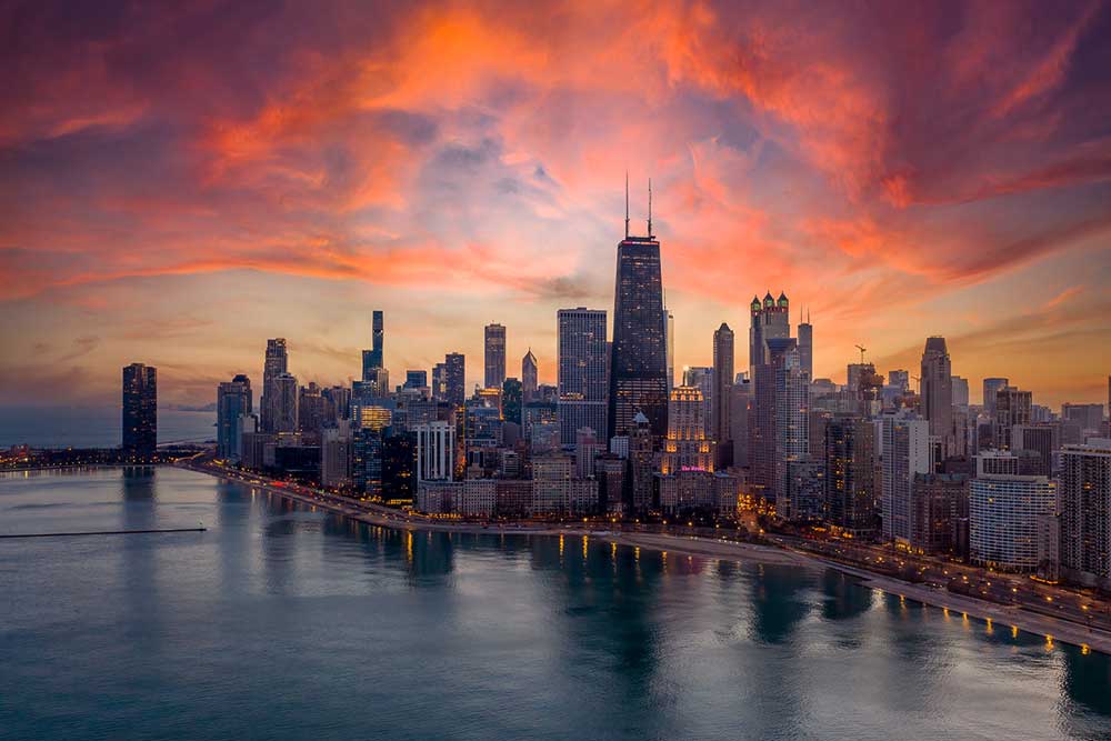 An aerial view of downtown Chicago, Illinois, at sunrise with Lake Michigan in the foreground.