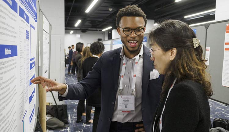 Two attendees at EPI|Lifestyle 2024 in Chicago discuss a scientific poster.