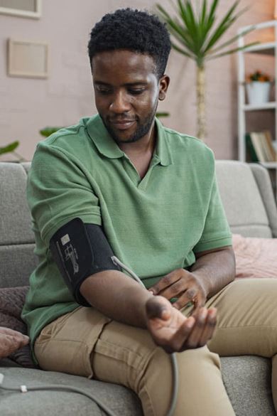 A young Black man checks his blood pressure.