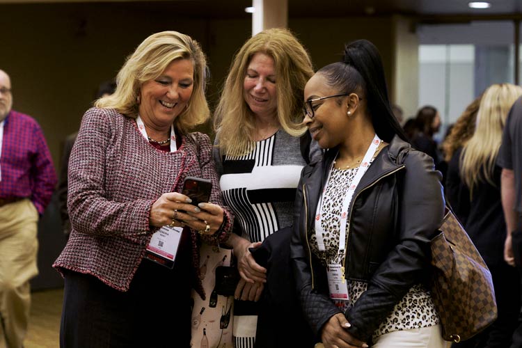 Three women admiring a photo on a phone at #ISC24 in Phoenix, Arizona. 