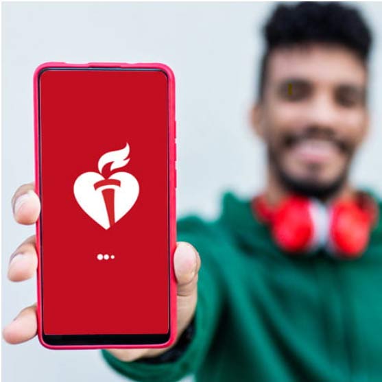 A man with headphones around his neck holds out his phone which shows the American Heart Association's Heart Event app.