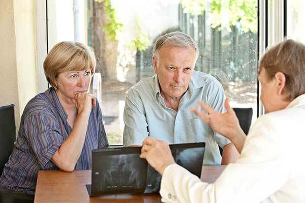Concerned older couple looks at Xrays with a doctor