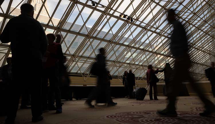 Attendees at #ReSS23 in Los Angeles are silhouetted against a skylight.