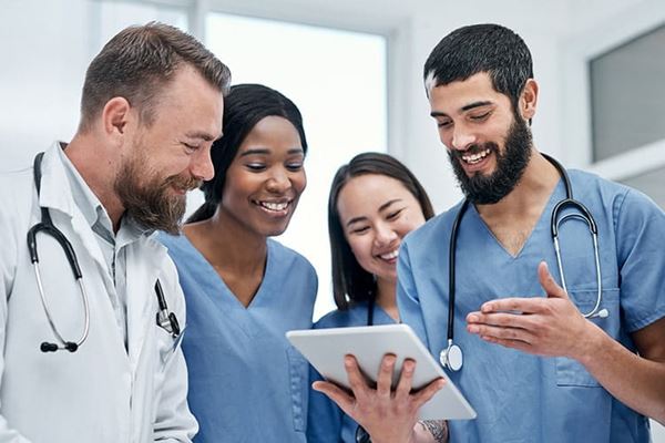 A diverse group of medical practitioners using a digital tablet together in a hospital.