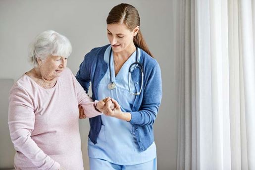 Caregiver nurse is holding hand of senior female