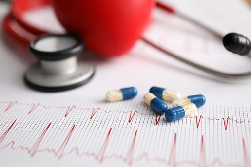 Stethoscope and capsule with medicine lie on form with cardiogram