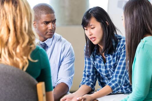 emotional Asian woman talks in group therapy
