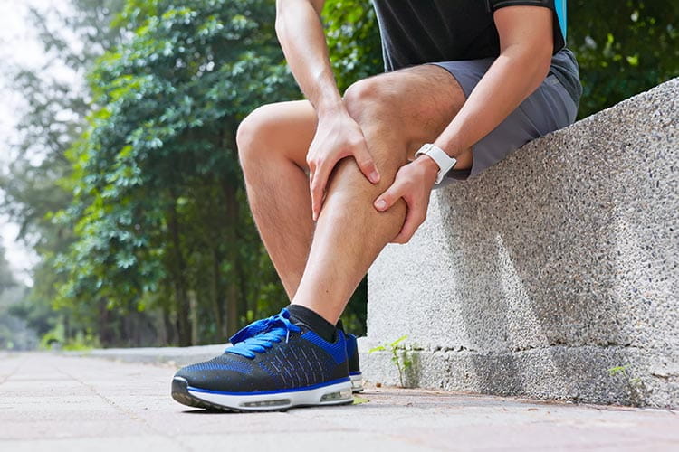 Runner sitting on curb holding knee