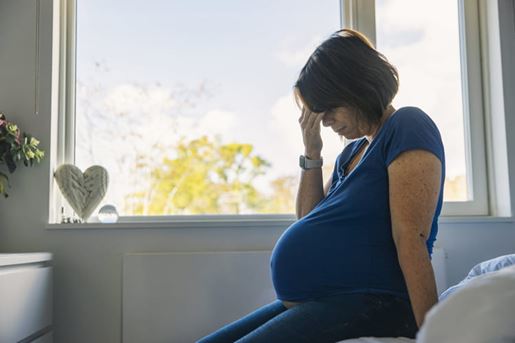 mature pregnant woman sitting on bed