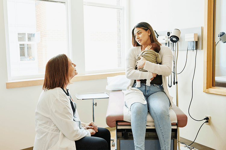 Physician talking with Mom with new born in exam room