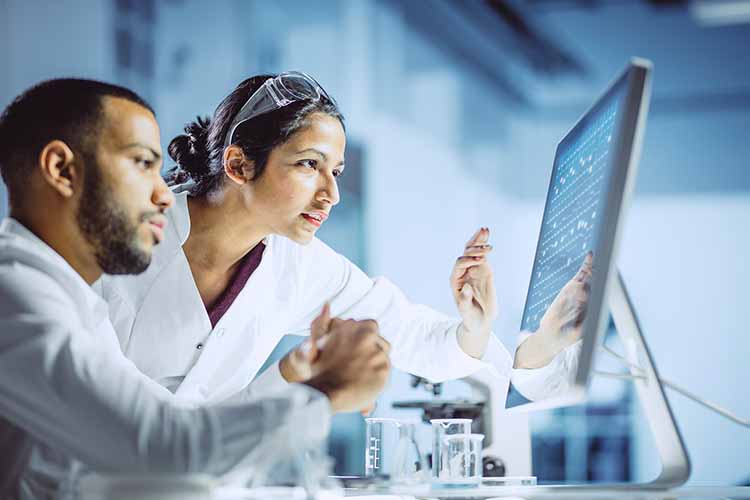 Two scientists in lab coats looking at monitor