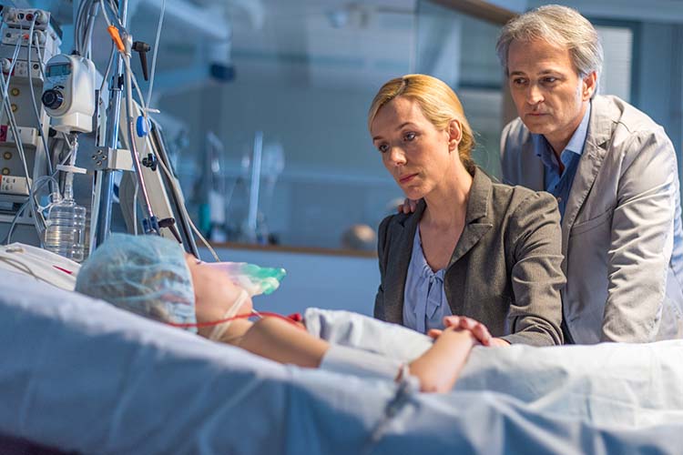 parents visiting young child in hospital bed