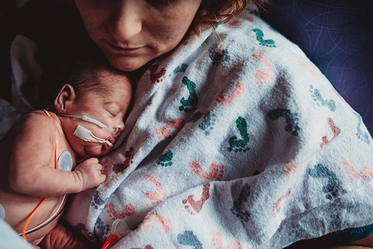 premature infant held by mother in hospital