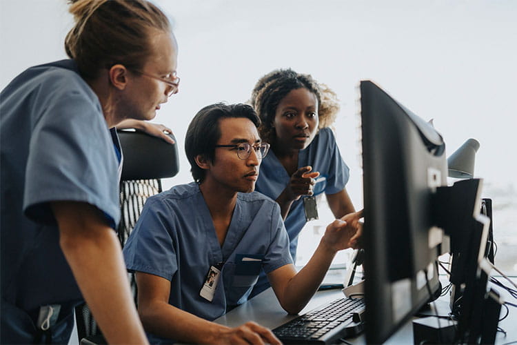 Three medical professionals looking at a computer monitor